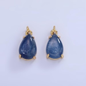 May include: Two gold teardrop-shaped pendants with blue gemstone inserts.