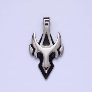 May include: A silver pendant with a black enamel design. The pendant features a stylized, abstract design with a pointed bottom and a loop at the top for attaching a chain.