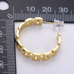 May include: Gold-toned hoop earrings with a chain-link design. The earrings are approximately 2 cm in diameter.