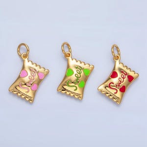 May include: Three gold charm pendants shaped like candy bags with the word "Sweet" written on them. Each bag has a different colored heart: pink, green, and red.