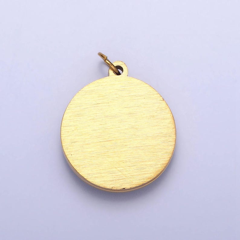 May include: A gold-colored round pendant with a smooth, brushed finish. The pendant has a loop at the top for attaching a chain.