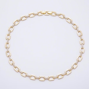 May include: A gold-tone chain necklace featuring rectangular links. Each link is embellished with small, clear, sparkling stones set along the edges, creating a continuous, shimmering pattern around the entire length of the jewelry piece.