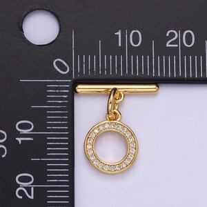 Pode incluir: Fecho de correr dourado com um pingente redondo com um c&iacute;rculo de pedras de cristal transparentes.