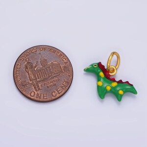 May include: A green and red enamel dinosaur charm with gold accents. The charm is about the size of a US penny.