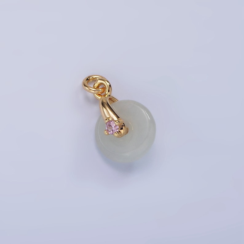 Pu&ograve; includere: Un ciondolo in oro con un disco di giada bianca e una pietra preziosa rosa. Il ciondolo &egrave; progettato per essere utilizzato come un ciondolo o una perla su un braccialetto.