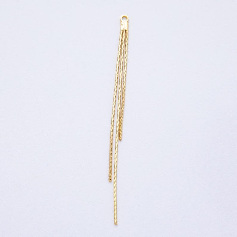 May include: A gold-colored jewelry component with a loop at the top and three dangling chains. The chains are thin and textured, creating a delicate, elegant appearance. The component is designed for jewelry making.