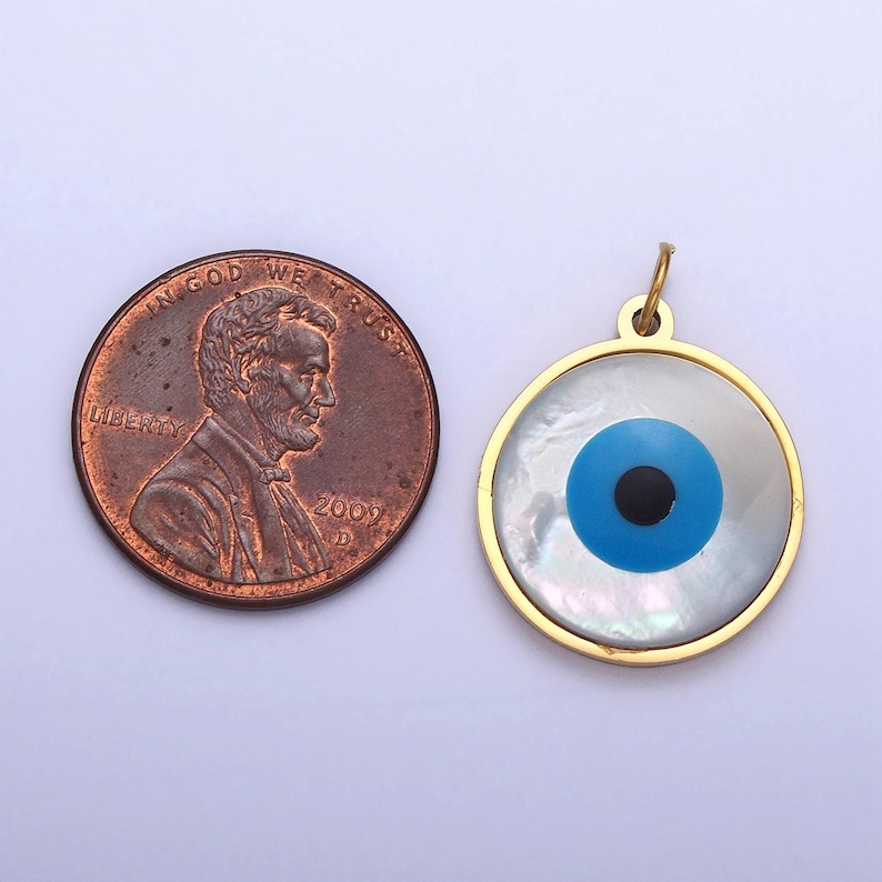 May include: Gold-toned pendant with a blue and black evil eye design set in a white mother-of-pearl shell. The pendant is about the size of a US penny.
