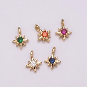 May include: Five gold star-shaped charms with different colored gemstones in the center. The charms are on a white background.