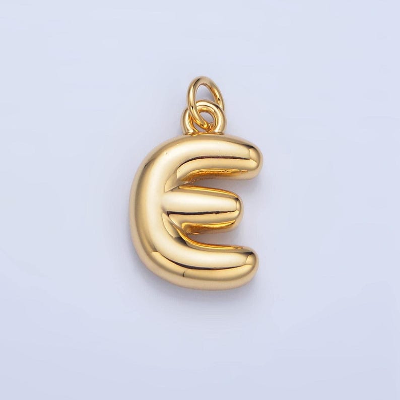 May include: A gold-colored charm in the shape of the letter 'E'. The charm is made of metal and has a smooth, shiny finish.