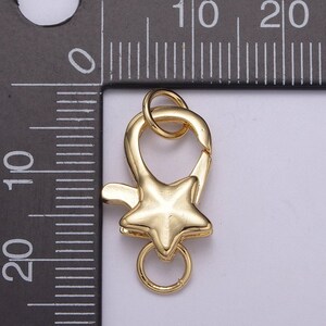 May include: Gold-toned metal star-shaped lobster clasp with a ring. The clasp is approximately 1 inch in length.