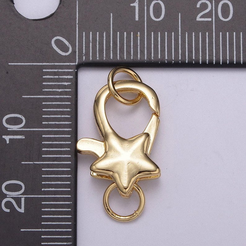 May include: Gold-toned metal star-shaped lobster clasp with a ring. The clasp is approximately 1 inch in length.