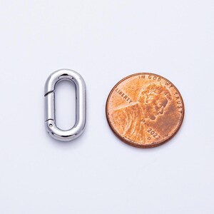 以下が含まれることがあります： 光沢のある銀色の楕円形の留め金と、米国のペニー。留め金にはヒンジ付きの開口部があります。ペニーには人物の横顔と「Liberty」と「In God We Trust」という言葉、そして2022年が示されています。