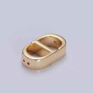 May include: Gold-toned metal connector with a double-loop design. The connector has a smooth, polished finish and is ideal for jewelry making or crafting projects.