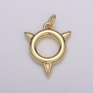 May include: Gold-toned pendant charm with a circular ring and three pointed spikes. The charm has a loop at the top for attaching to a necklace or bracelet.