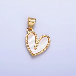 Puede incluir: Colgante de corazón de oro con incrustación de nácar blanco. El colgante tiene un borde de cuentas.