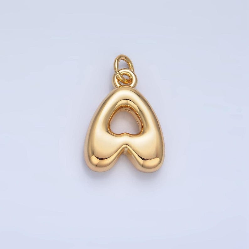 May include: A gold-colored charm in the shape of the letter A. The charm has a hollow center in the shape of a heart.