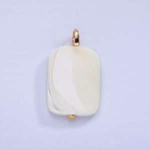 May include: A rectangular pendant with a creamy white, marbled appearance. The pendant has a gold-colored bail at the top and a small gold bead at the bottom. The overall design is simple and elegant.