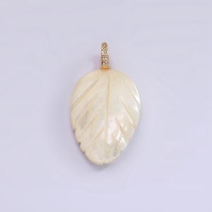 May include: A white mother of pearl leaf pendant with a gold chain and clear cubic zirconia stones.