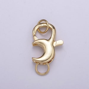 May include: Gold-toned metal clasp with a crescent moon design. The clasp has two rings for attaching to a necklace or bracelet.