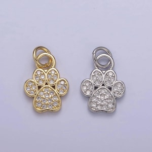 May include: Two paw print charms, one gold and one silver, with clear crystal accents. The charms have a loop for attaching to a necklace or bracelet.
