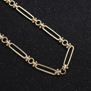 May include: A gold chain necklace with a simple, linked design. The chain is made of oval-shaped links with small round beads at each connection point.