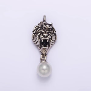 May include: A silver pendant featuring a detailed lion's head with a crown and a dangling pearl.