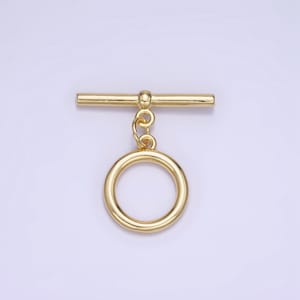 Pode incluir: Fecho de correr de metal dourado com um anel redondo. O fecho é uma barra com um laço redondo em cada extremidade. O anel é preso à barra por uma pequena corrente.