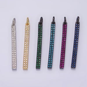 May include: Six different colored bar pendants with a pave setting of small stones. The pendants are silver, gold, green, blue, pink, and blue. Each pendant has a jump ring at the top for attaching to a chain.