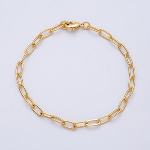 May include: A gold-colored chain bracelet with oval links and a lobster clasp. The bracelet is made of a shiny, metallic material and is displayed on a white background. The links are evenly spaced, creating a simple yet elegant design.