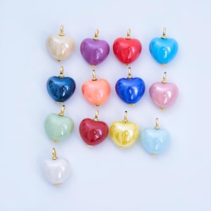May include: A collection of heart-shaped pendants in various colors, including red, blue, pink, and green. Each pendant has a gold-colored bail for attaching to a chain. The pendants are glossy and smooth, with a polished finish.