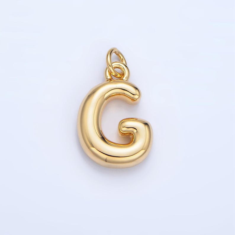 May include: Gold-colored letter G charm pendant. The letter is stylized with a rounded, bubbly design.