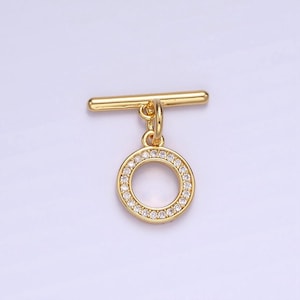Pode incluir: Fecho de correr dourado com um pingente redondo incrustado com strass transparentes.