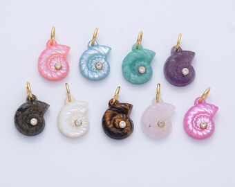 May include: A collection of ten seashell-shaped pendants in various colors, including pink, blue, green, and purple. Each pendant has a gold-colored bail and a small, clear gemstone in the center. The pendants are displayed on a light background.