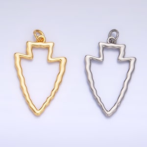 May include: Two arrowhead shaped pendants, one gold and one silver, with a textured edge. The pendants are both open and have a loop at the top for attaching to a chain.