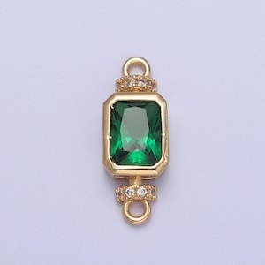 May include: Gold-tone connector charm with a green emerald-shaped gemstone surrounded by clear cubic zirconia stones.