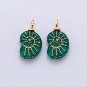 May include: Two green glass pendants with a spiral design in gold. Each pendant has a gold-coloured loop at the top for hanging. The pendants are a vibrant green colour and have a detailed, etched pattern.