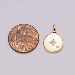 May include: Gold pendant featuring a small diamond star and a single diamond. The pendant is approximately the size of a UK penny.