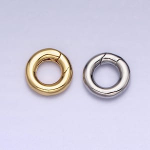 May include: Two metal ring clasps, one gold and one silver, are shown on a white background. The clasps are round and have a smooth finish.