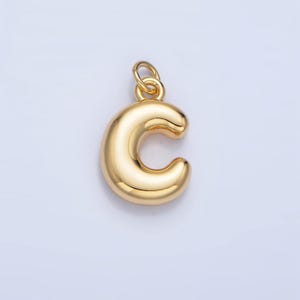 May include: A gold-colored charm in the shape of the letter C. The charm is smooth and has a shiny finish.