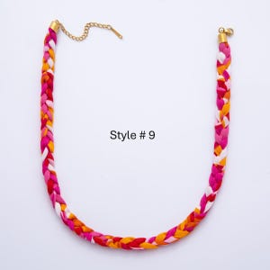 May include: Braided fabric necklace in shades of pink, red, yellow, and white. The necklace has a gold-colored chain and clasp. The text "Style # 9" is visible on the image.