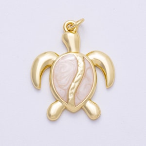 May include: A gold-colored turtle pendant with a light pink and white marbled center. The pendant has a loop at the top for attaching to a chain or cord. The turtle's flippers and head are rounded and smooth.
