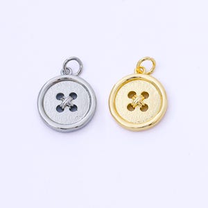 Op de afbeelding: Twee ronde knoopbedels, één zilverkleurig en één goudkleurig, elk met een viergatsontwerp. De bedels hebben een lus aan de bovenkant om aan een ketting of een ander sieradenonderdeel te bevestigen. Ideaal voor het maken van sieraden.