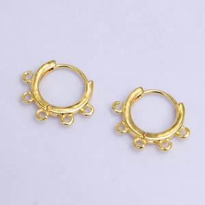 May include: A pair of gold-toned hoop earrings with five jump rings on each hoop. The hoops are smooth and have a polished finish.