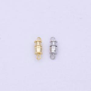 Könnte beinhalten: Zwei Magnetverschlüsse zum Schmuck basteln. Einer ist golden und der andere ist silber.