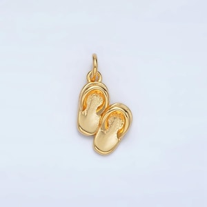 May include: A gold charm in the shape of a pair of flip flops. The charm is a popular choice for jewelry making and can be used to create necklaces, bracelets, and earrings.