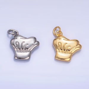 May include: Two chef hat charms, one silver and one gold. The charms are detailed with a chef hat design and have a loop for attaching to a necklace or bracelet.