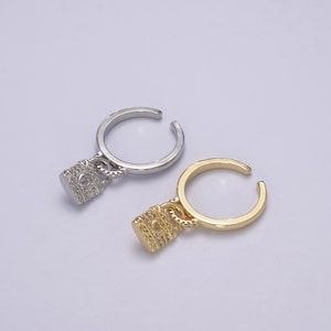 May include: Two adjustable rings with a padlock charm. The ring on the left is silver and the ring on the right is gold.