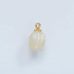 May include: A pearlescent white pendant in the shape of a tulip flower, with a gold-colored loop at the top. The pendant has a smooth, glossy finish and is set against a white background.