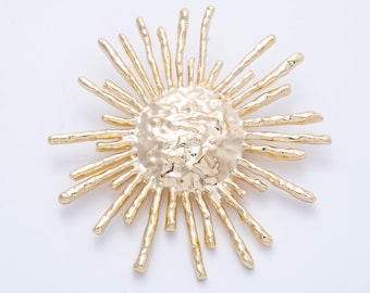 May include: A gold-colored sunburst brooch with a textured center and radiating spikes. The brooch has a bright, metallic finish and is likely made of metal. This accessory could be used to embellish clothing or accessories.