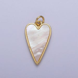 May include: A gold-toned pendant in the shape of a heart with a white mother-of-pearl inlay.